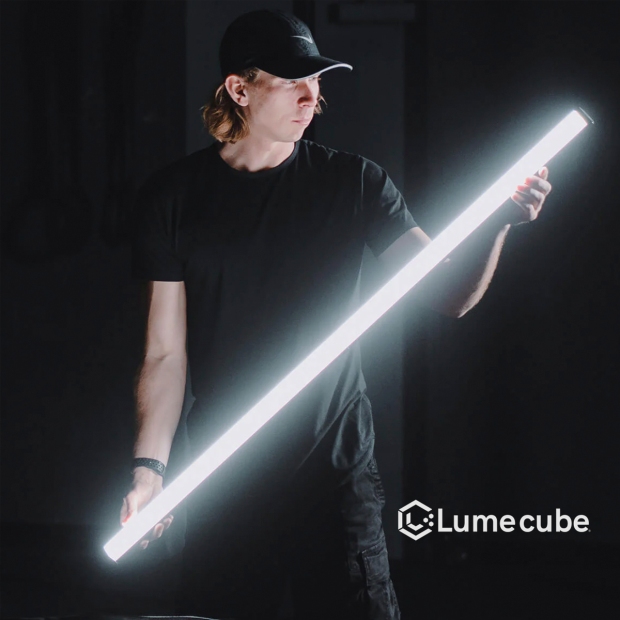man holding an illuminated LED tube light in a dark room.